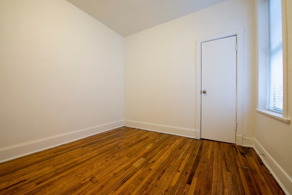 an empty room with wooden floors and a white door