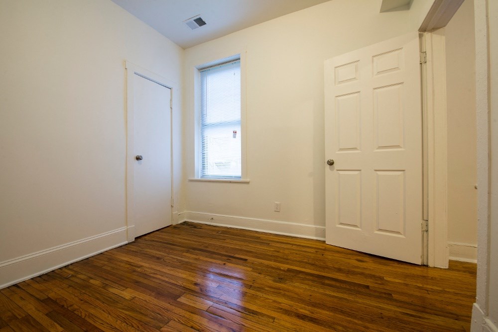 a bedroom with wooden floors and a white door and window