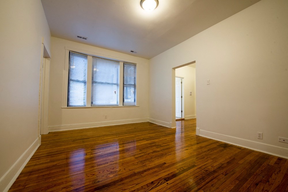 an empty living room with wood floors and a window