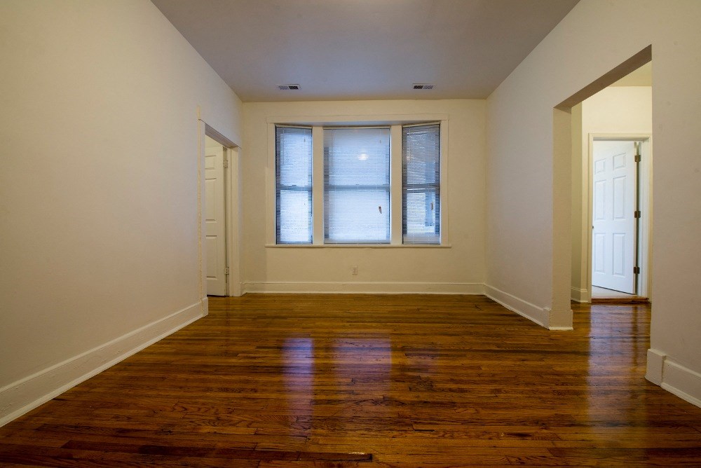 an empty living room with wood floors and a window