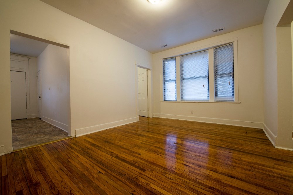 an empty living room with wood floors and a window