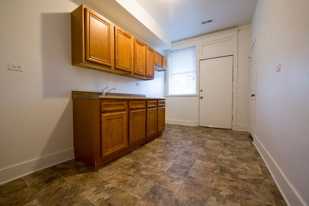 an empty kitchen with wooden cabinets and tile flooring
