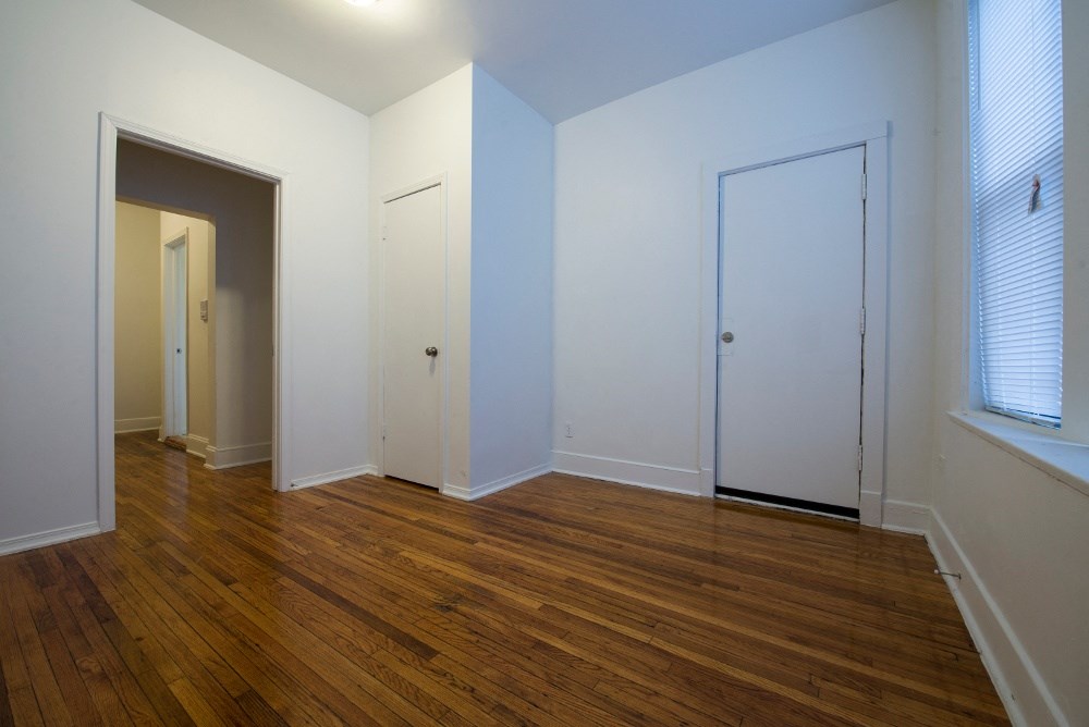 an empty living room with wood floors and white walls