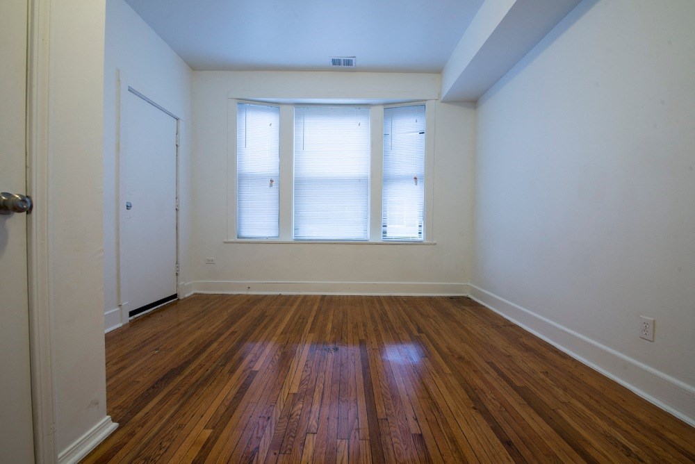 an empty living room with wood floors and a window