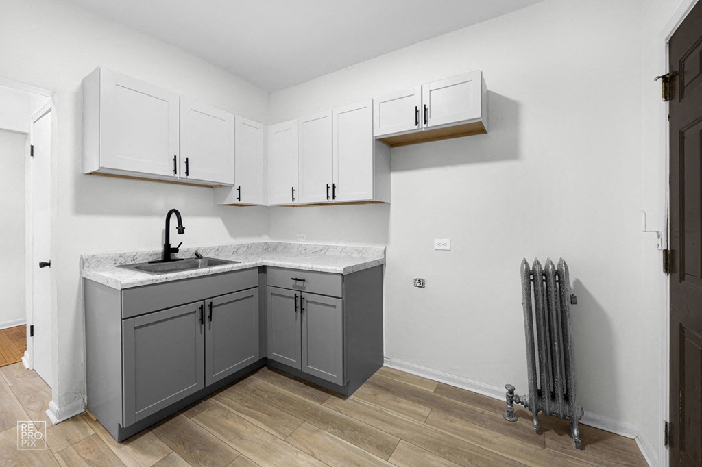 a renovated kitchen with gray and white cabinets and a sink