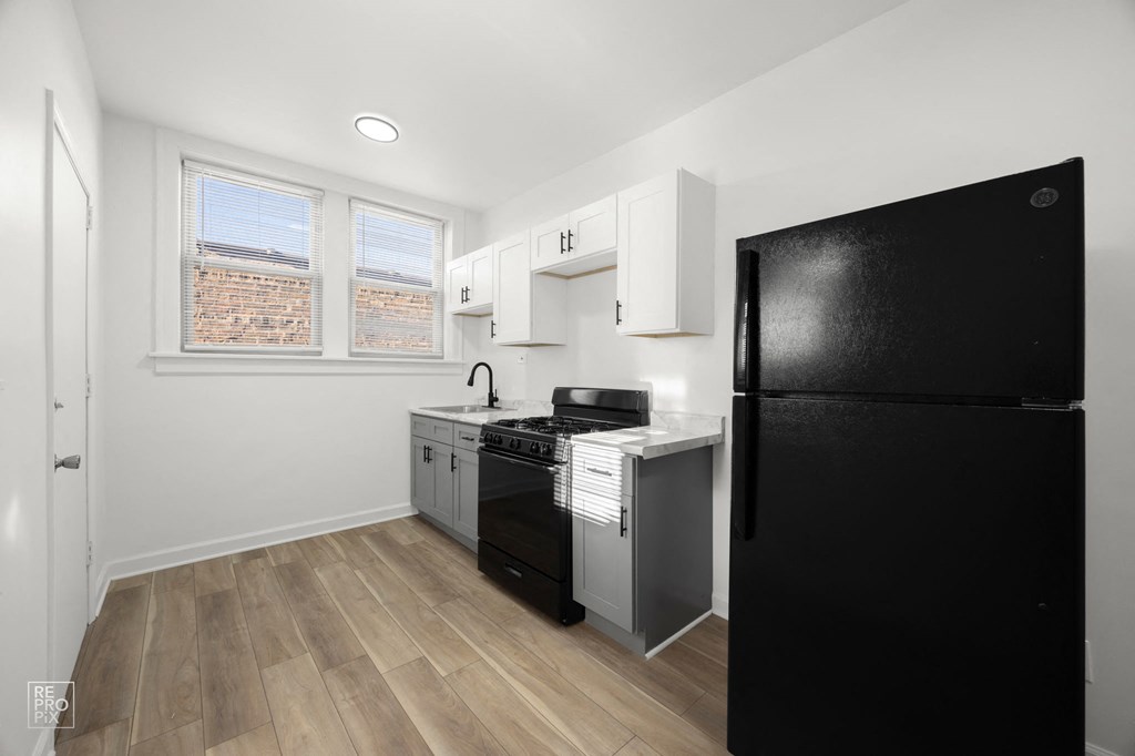 a kitchen with a black refrigerator and a stove