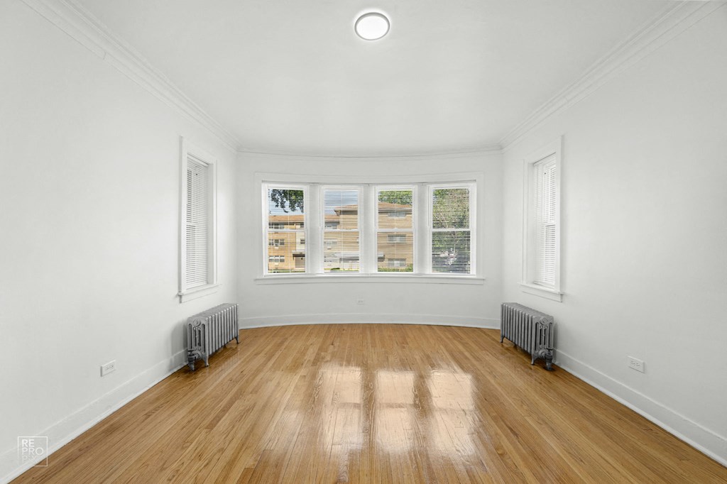 a living room with white walls and wood floors and a window