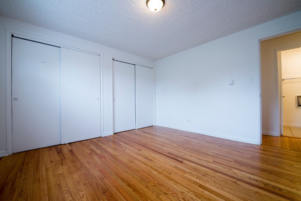 the living room of an apartment with wood flooring and white walls