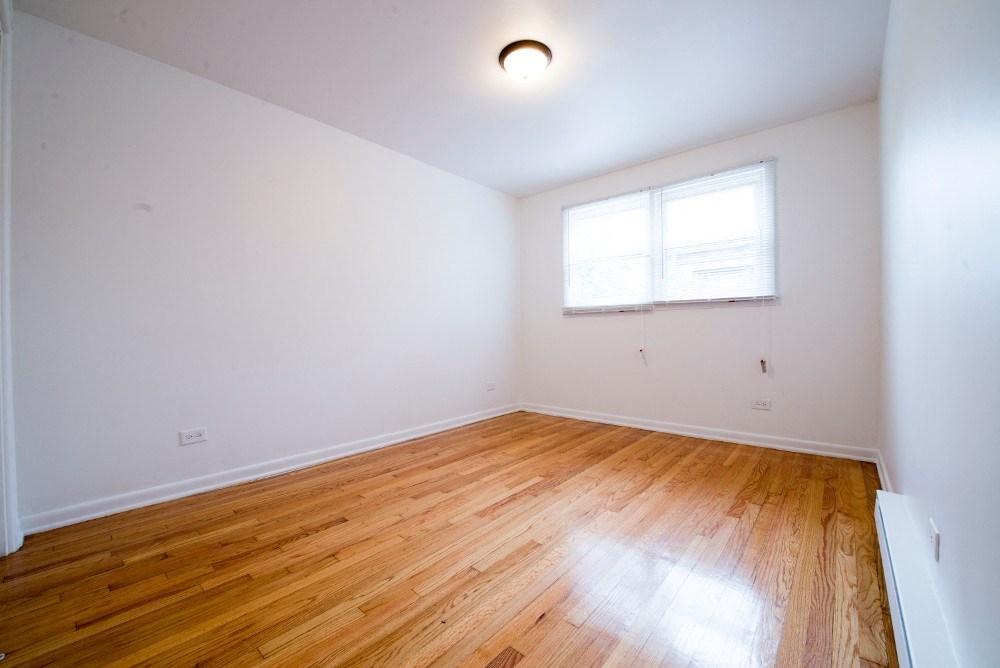an empty room with wood floors and a window