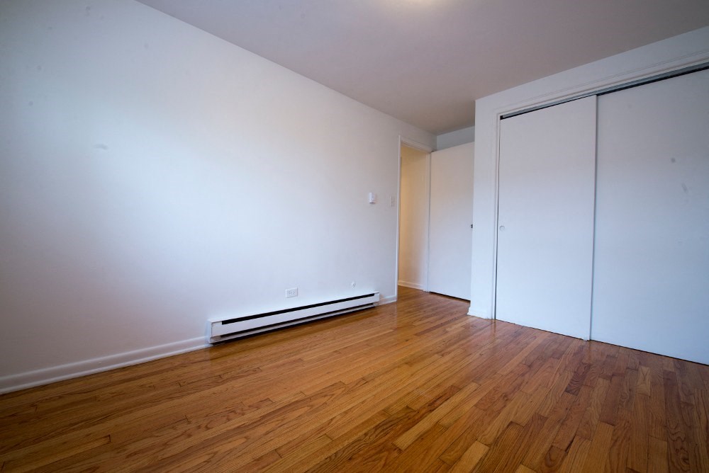 an empty room with wood floors and white walls