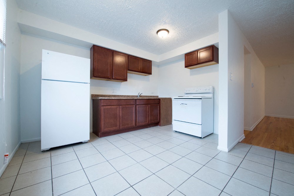 an empty kitchen with white appliances and wooden cabinets
