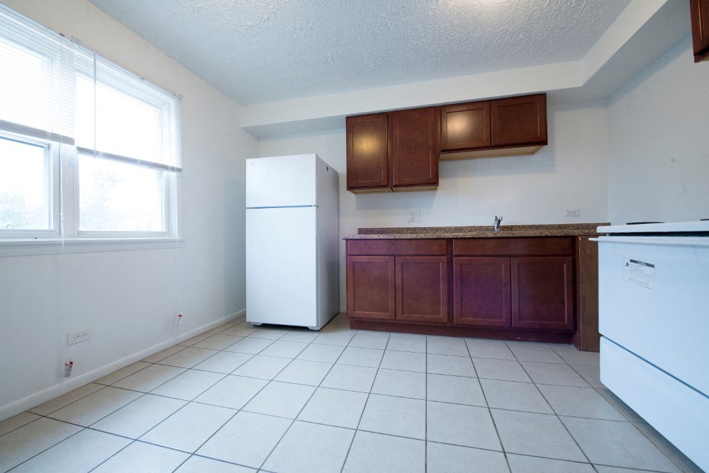 an empty kitchen with white appliances and wooden cabinets