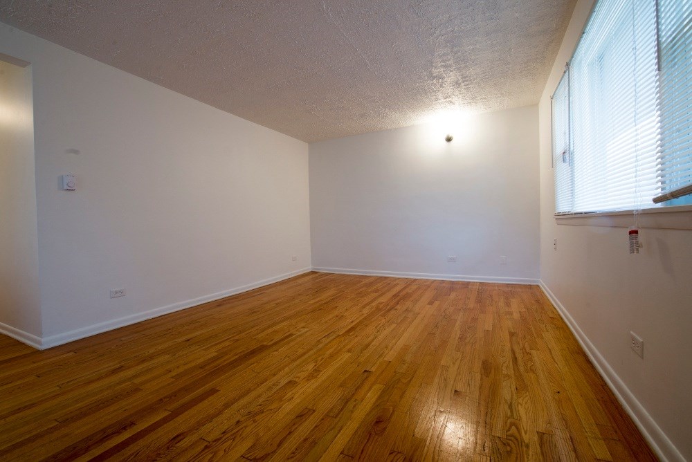 the bedroom of an empty house with wood floors and a large window