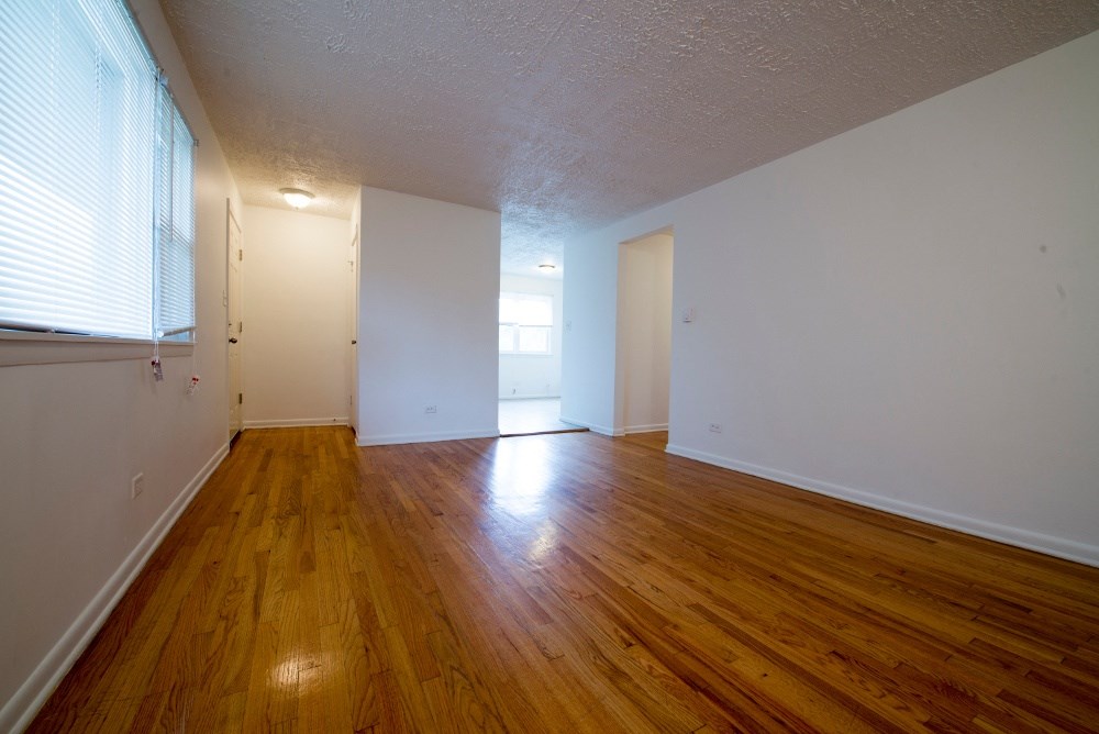 an empty living room with wood floors and white walls