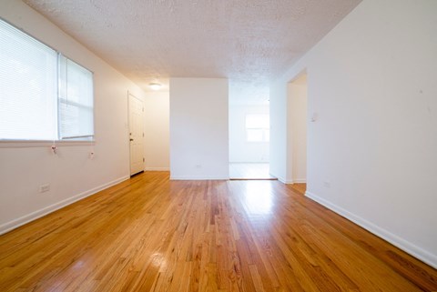 the living room and dining room of an apartment with wood floors and white walls