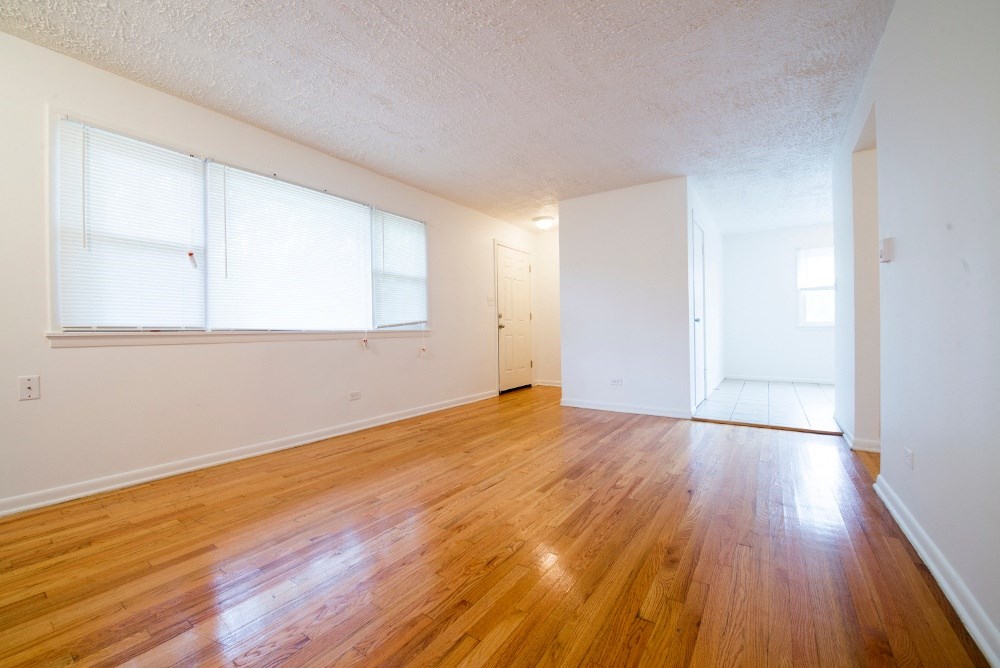an empty living room with hard wood floors and a window