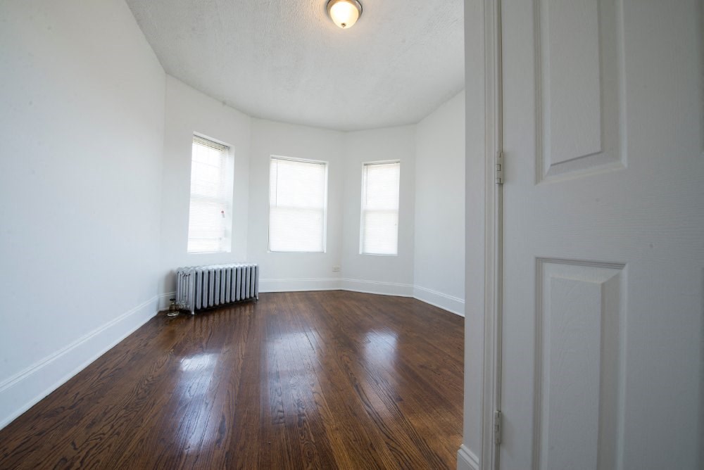 an empty room with white walls and wood floors and a radiator