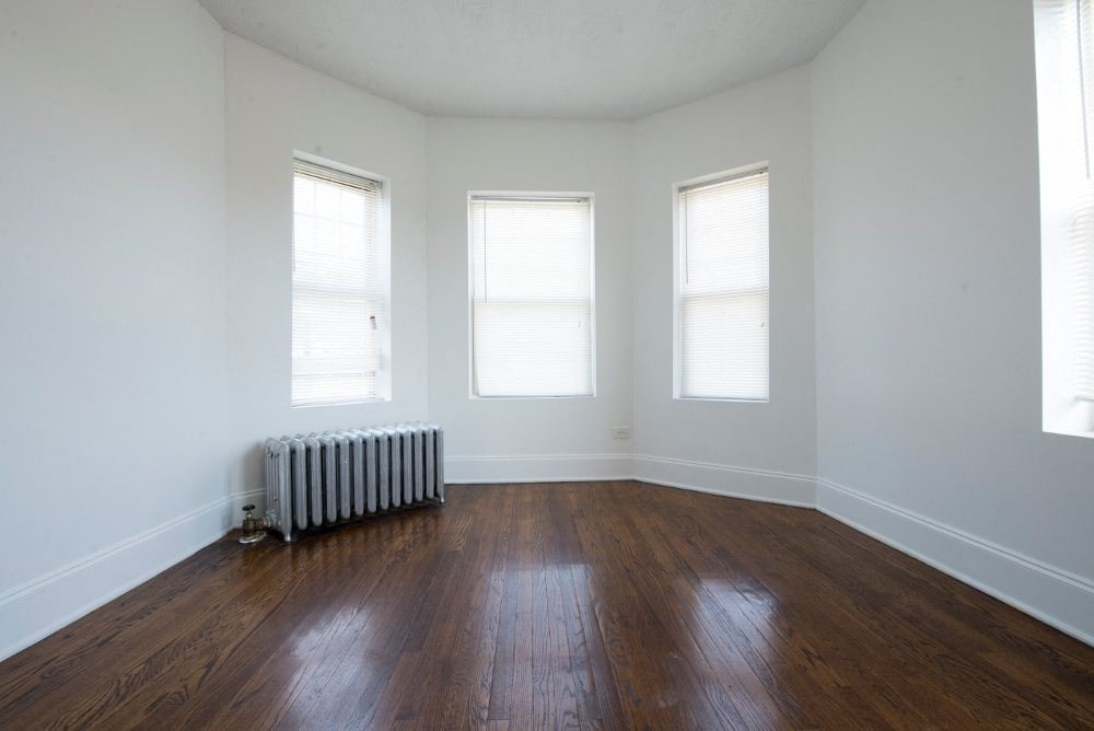 an empty room with a radiator and three windows