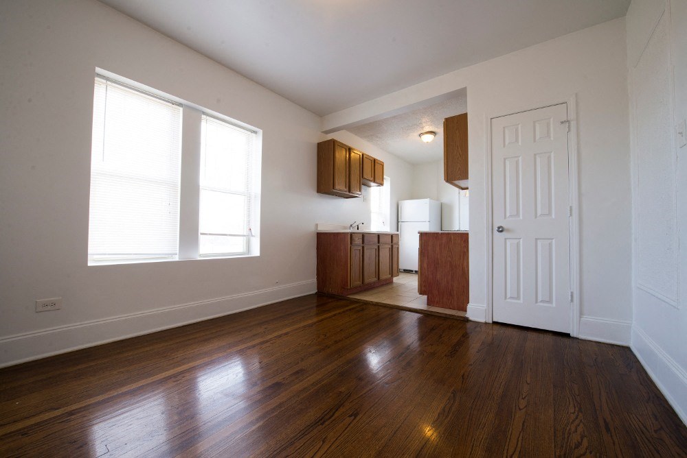 an empty living room and kitchen with wood floors and a white door