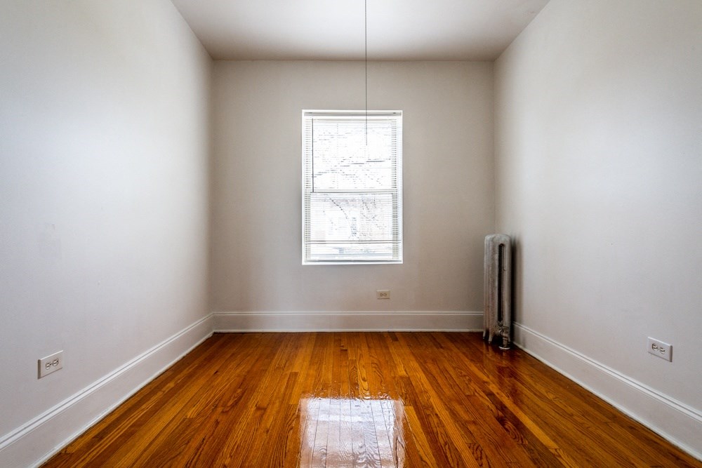 an empty room with wooden floors and a window