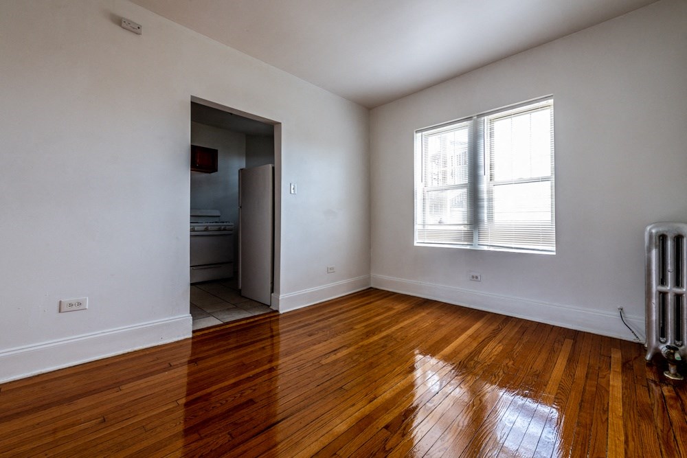 an empty living room with wooden floors and a window