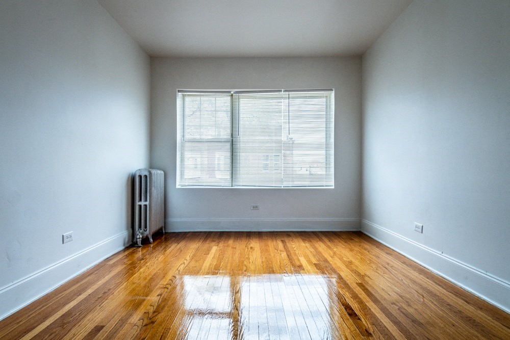 an empty room with wood floors and a window