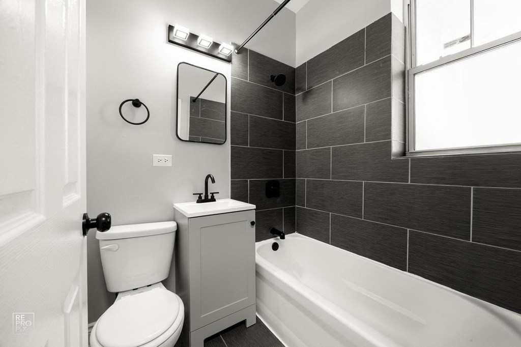 a black and white bathroom with a tub and a toilet