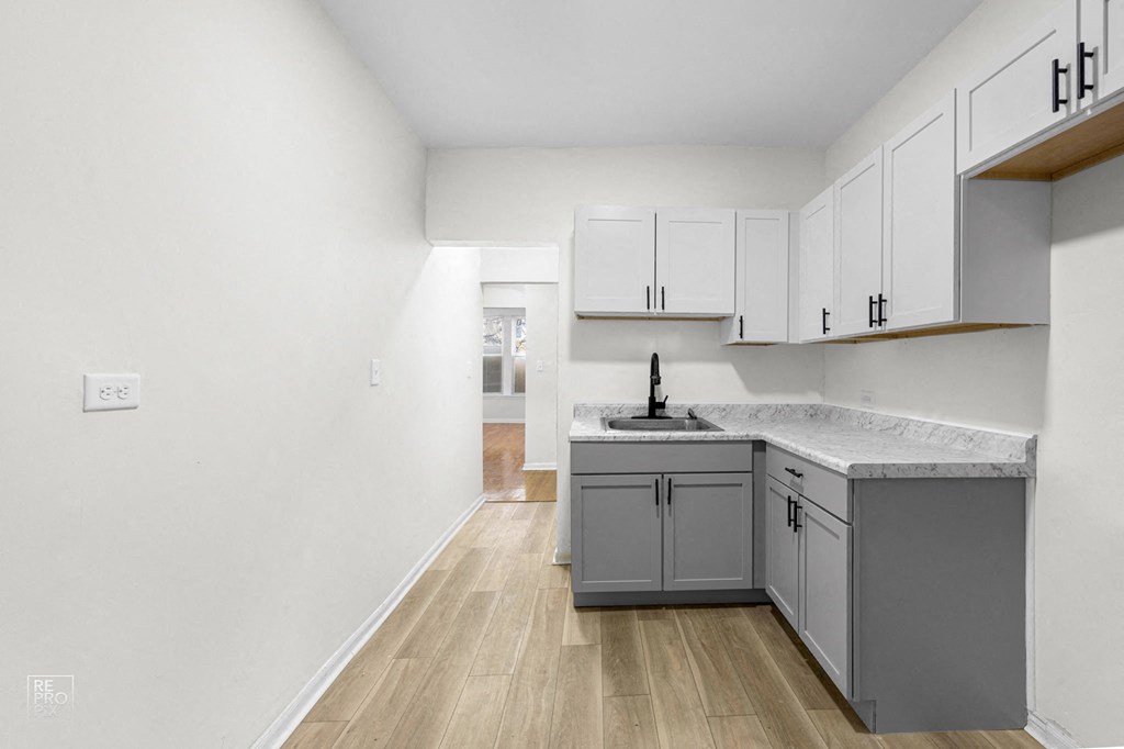 an empty kitchen with white cabinets and a gray counter top
