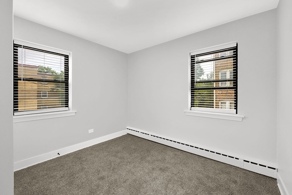 a bedroom with two windows and a carpeted floor