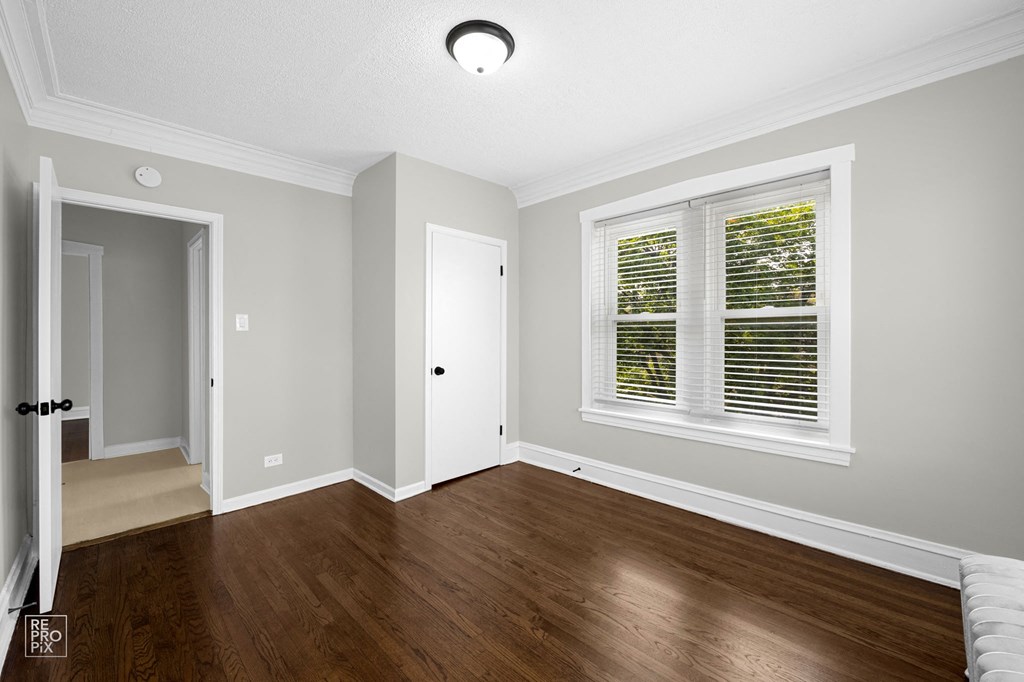 a bedroom with hardwood floors and grey walls