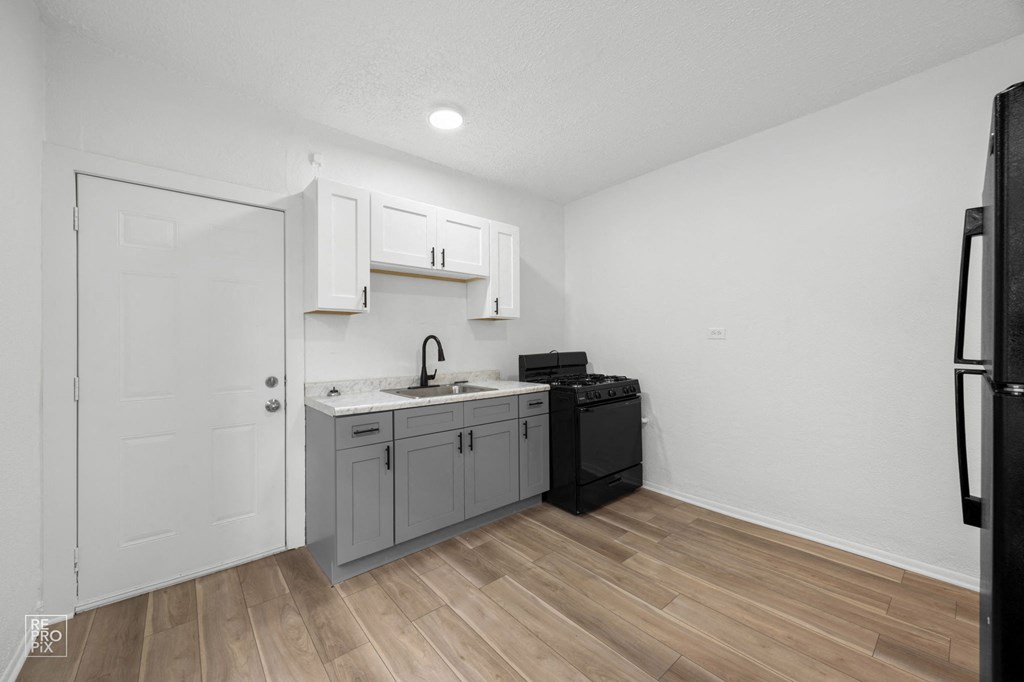 a renovated kitchen with white cabinets and a black stove and refrigerator