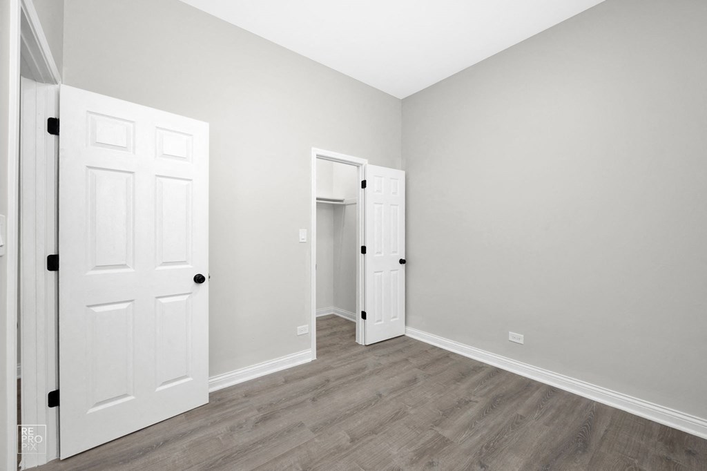 a bedroom with grey walls and a hardwood floor
