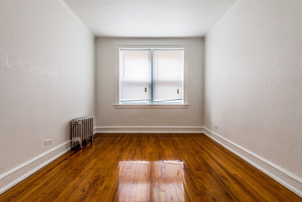 an empty room with wood floors and a window