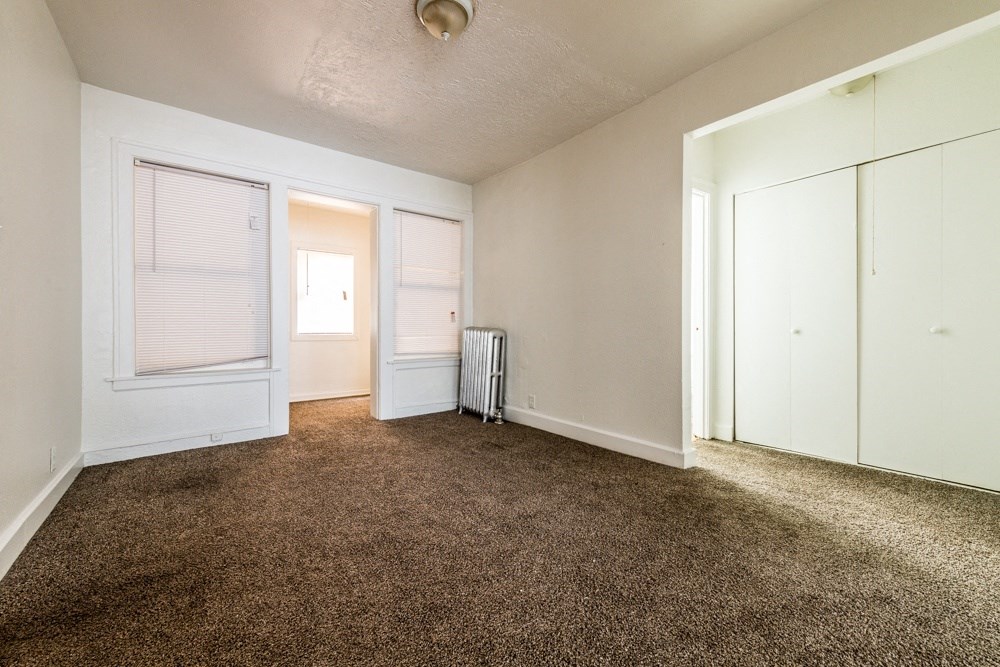 an empty living room with carpet and white doors