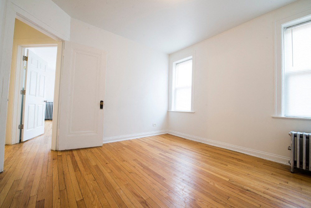 a living room with wood floors and white walls and a door