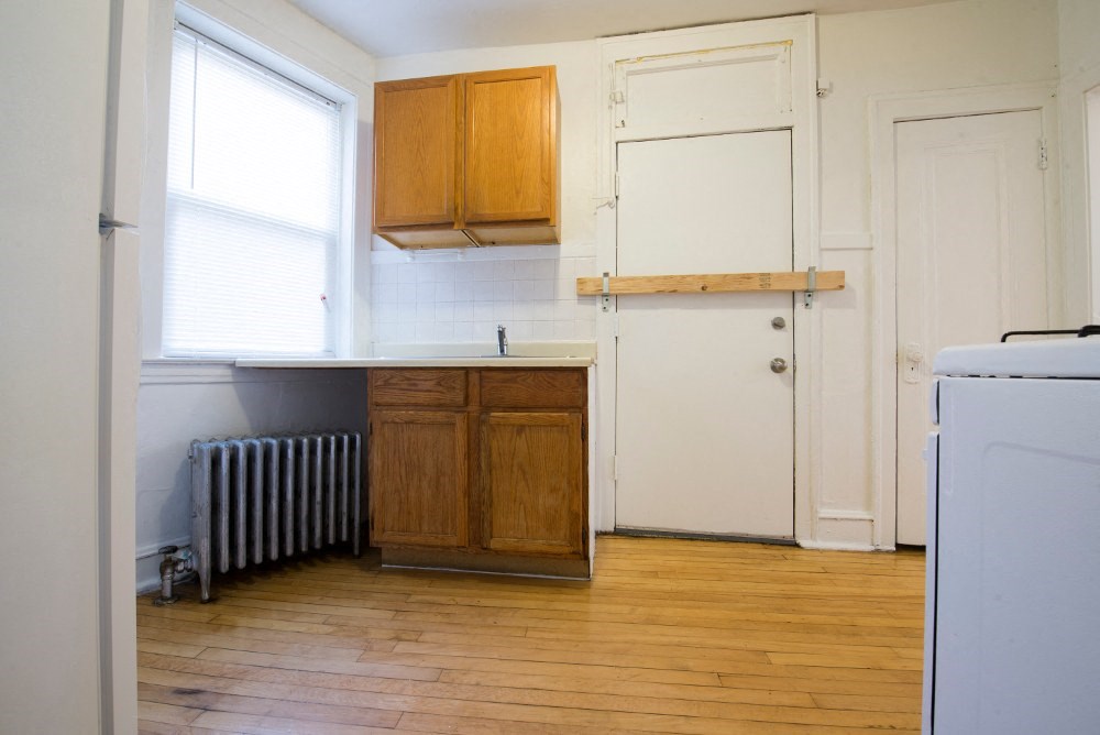 a kitchen with a wood floor and white cabinets and a radiator