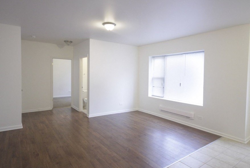 an empty living room with wood floors and a window