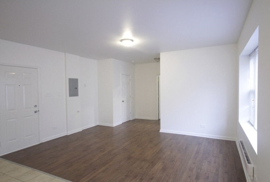 an empty living room with white walls and a wooden floor