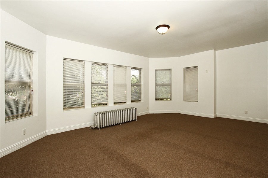 an empty living room with a heater and windows