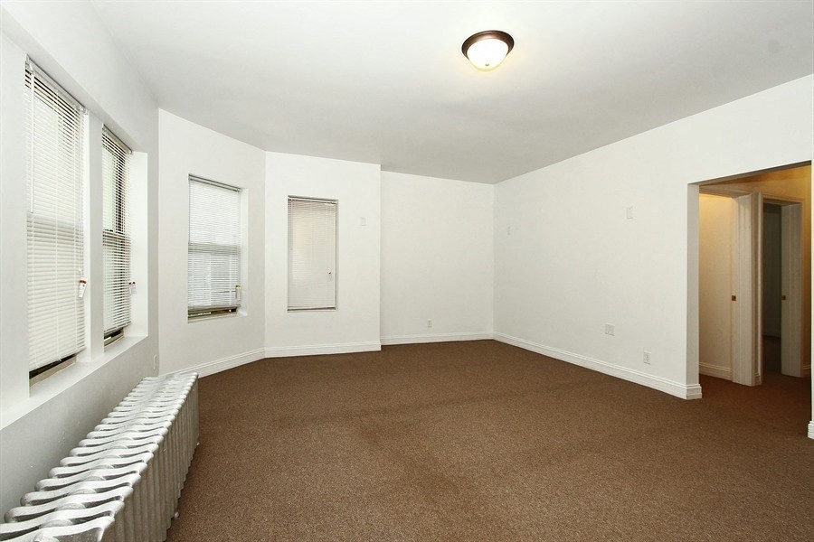 an empty living room with a carpeted floor and a window