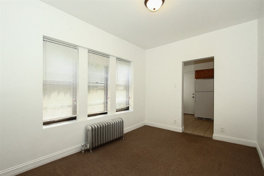 an empty living room with three windows and a heater