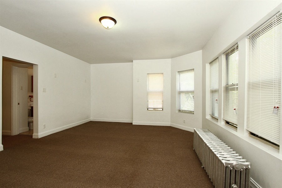 an empty living room with a radiator and windows
