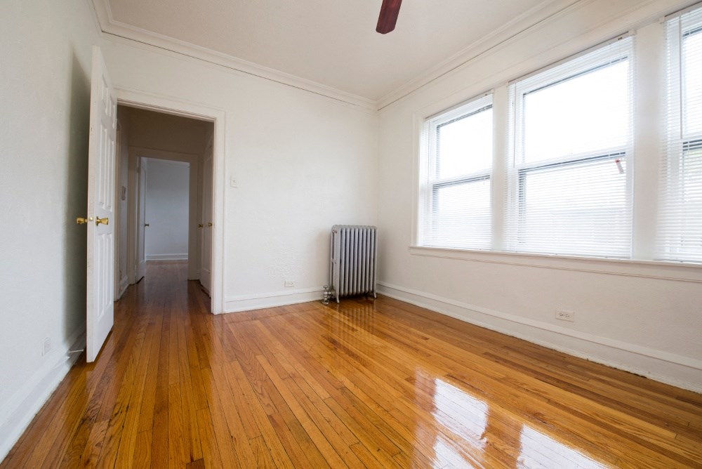 an empty room with wood floors and a radiator