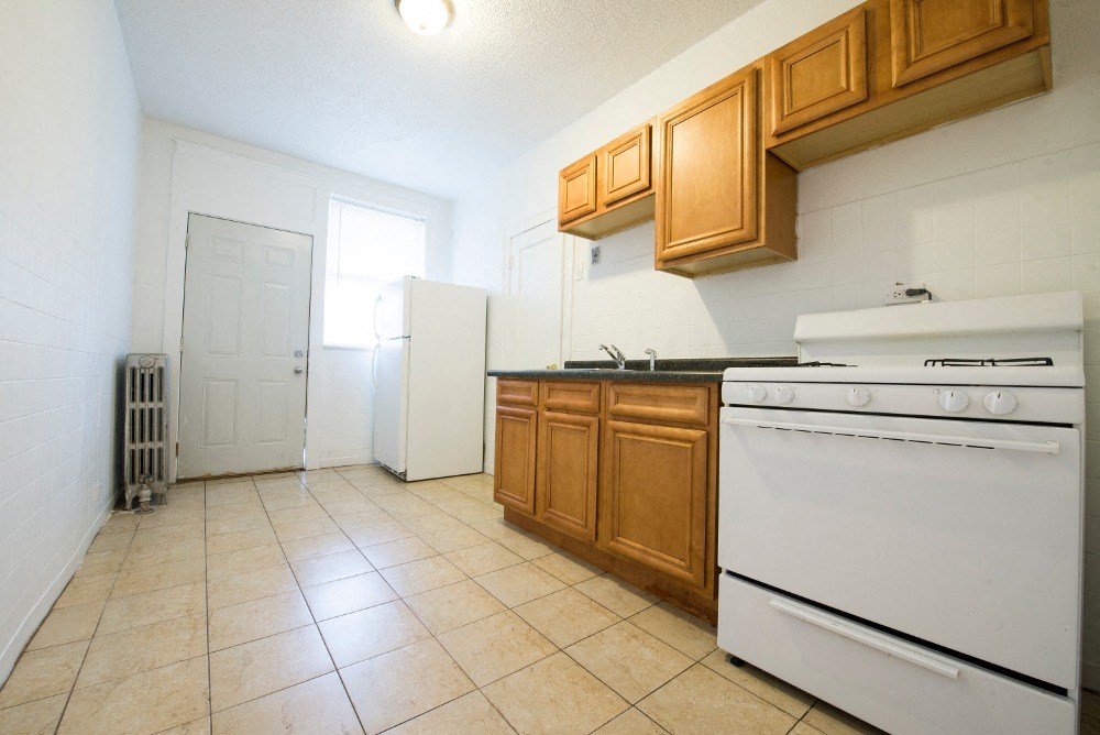 an empty kitchen with white appliances and wooden cabinets