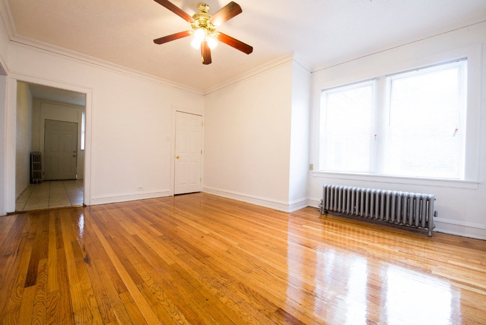 an empty living room with wood floors and a ceiling fan
