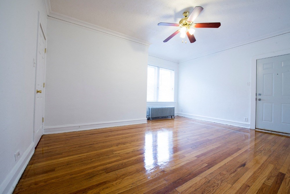 an empty living room with wood floors and a ceiling fan