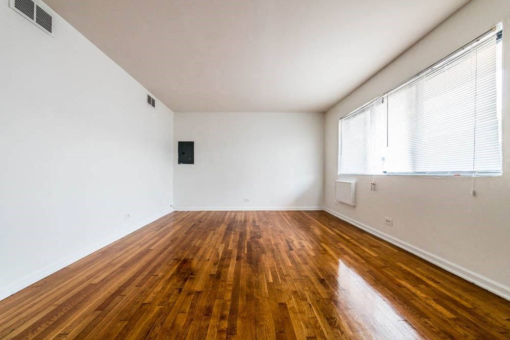 an empty room with wood floors and a large window