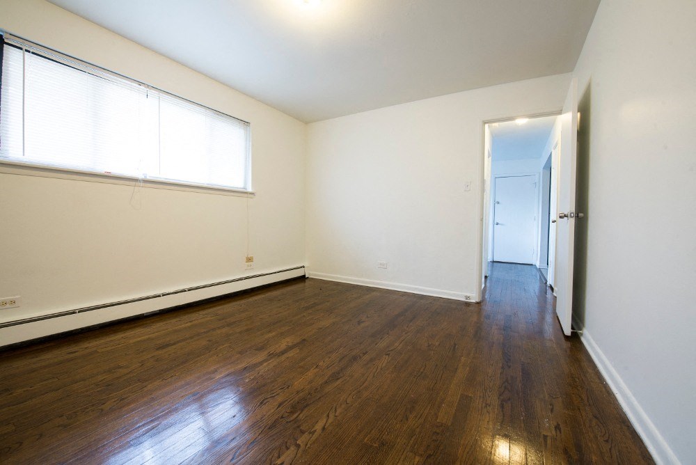 an empty living room with wood floors and white walls