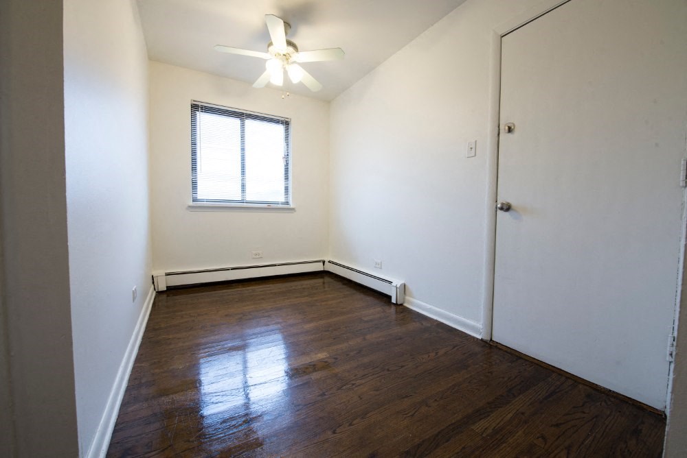 an empty room with wooden floors and a window and a ceiling fan