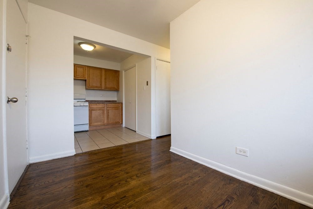 a living room and kitchen with white walls and wood floors